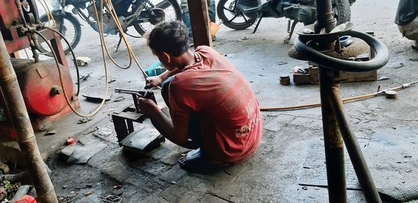 Rear view of man working on metal