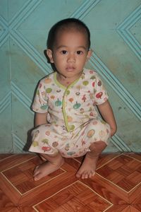 Portrait of cute baby girl sitting on floor at home
