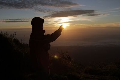 Silhouette person standing  against sky during sunset