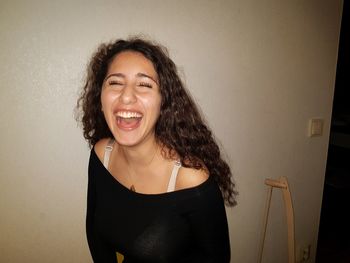 Portrait of smiling young woman against wall at home