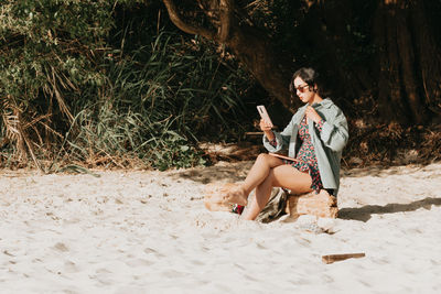 Young woman sitting on sand at beach