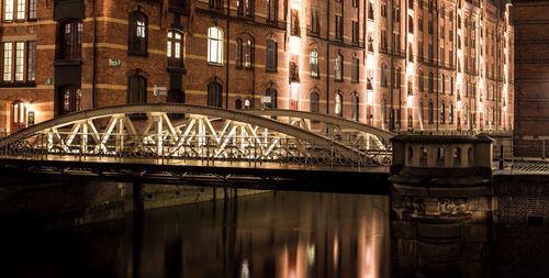 Illuminated bridge over river in city at night
