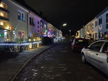 Cars on illuminated street amidst buildings in city at night