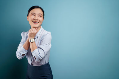 Portrait of a smiling young woman against blue background