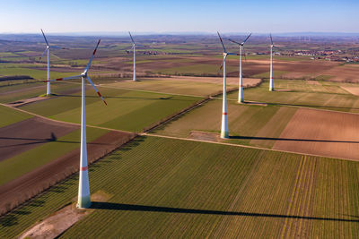 A wind farm with wind turbines between fields seen from the air from high above