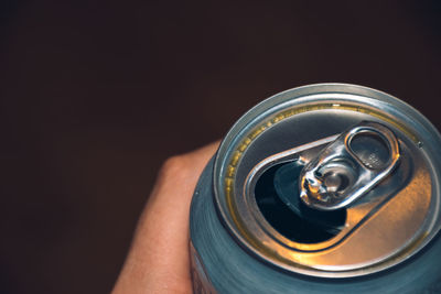 Close-up of hand holding drink against black background