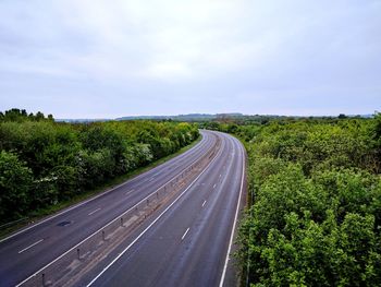 Road amidst green landscape against sky