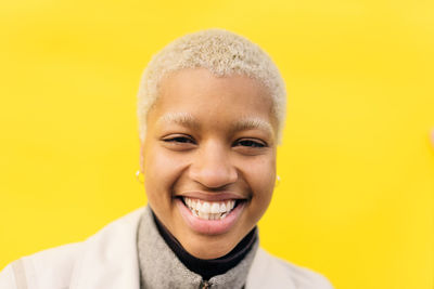 Portrait of smiling young female standing against yellow background