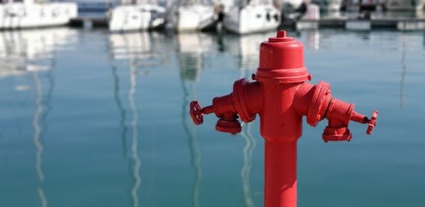 Close-up of red fire hydrant in front of harbour