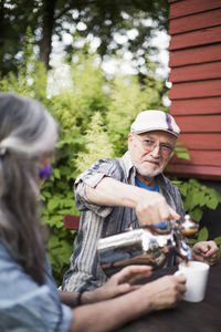 Senior man looking at woman while pouring coffee in cup