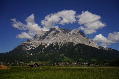 Scenic view of field by mountains against sky