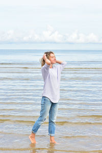 Full length of young woman standing at beach