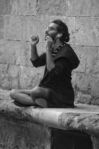 Side view of woman sitting against wall