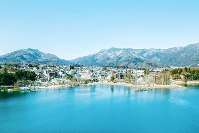 Scenic view of lake by buildings against clear blue sky