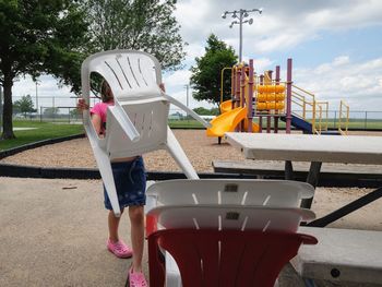 Girl keeping chair by picnic table at park