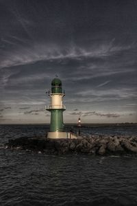 Lighthouse by sea against sky