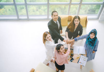 High angle view of business people stacking hands in office