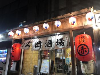 Illuminated lanterns hanging by building at night