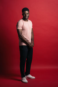 Portrait of young man standing against red background