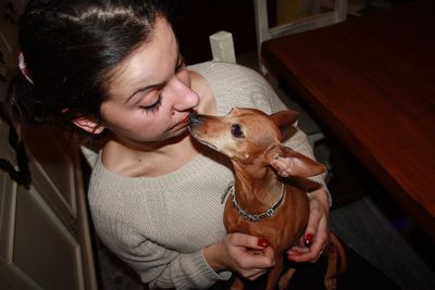 Close-up of woman holding dog sitting at home