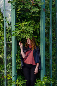 Portrait of young woman standing by plants