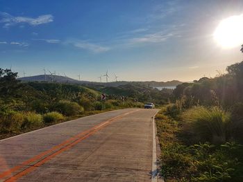 Road by trees against sky