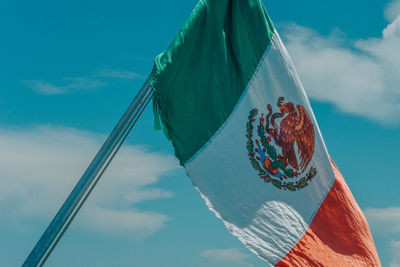 Low angle view of flags hanging against blue sky