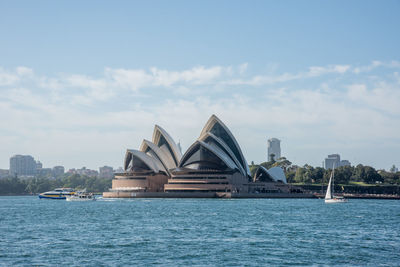 View of buildings by sea against cloudy sky