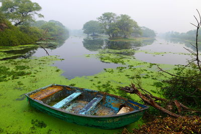 Abandoned boat moored in lake against sky