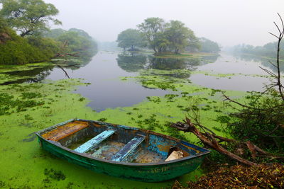 Abandoned boat moored in lake against sky