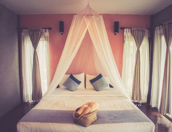 Towels in wicker basket on bed at home