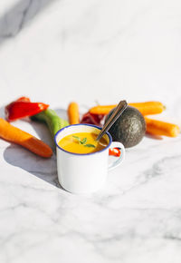 Top view of vegan pumpkin cream in an enameled mug with vegetables, peppers leek and tomatoes