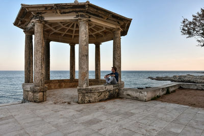 Gazebo sitting on shore by sea against sky