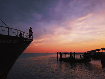 Silhouette pier over sea against sky during sunset