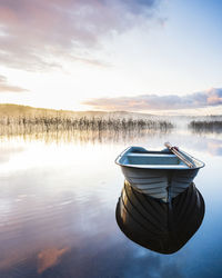 Boat moored on lake against sky