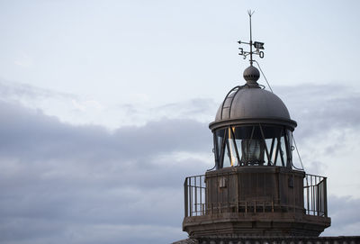 Low angle view of lighthouse by building against sky