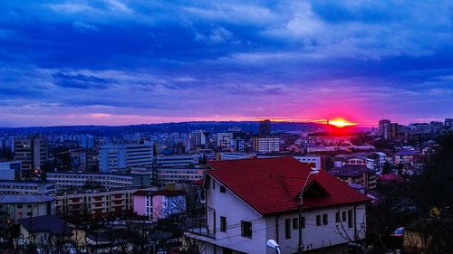 Illuminated cityscape against sky at sunset