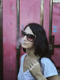 Woman wearing sunglasses smoking outdoors