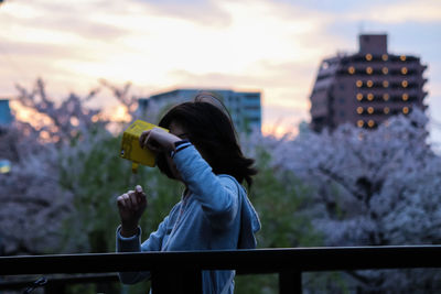 Rear view of woman photographing against sky