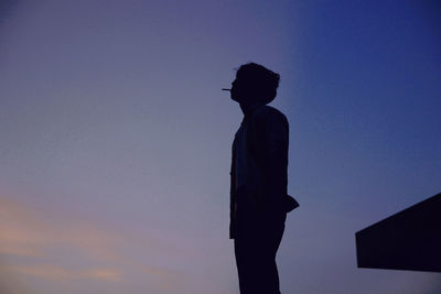 Low angle view of silhouette man standing against sky during sunset