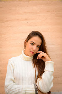 Portrait of a beautiful young woman against wall