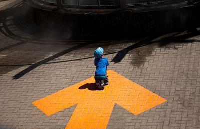 High angle view of boy walking on cobblestone