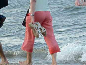 Rear view of man holding umbrella at sea