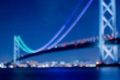 Defocused image of akashi strait bridge over sea against sky at night