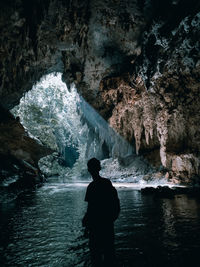 Rear view of man standing on rock in sea