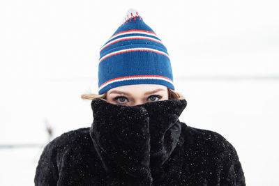 Young fashionable woman walks in the forest in winter and uses a mobile phone