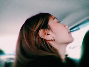 Close-up of young woman wearing earrings looking away in car