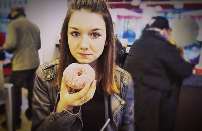 Portrait of beautiful woman eating donut at store