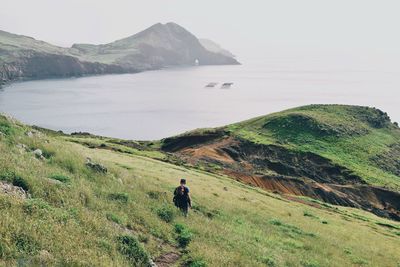 High angle view of man walking on cliff against sea