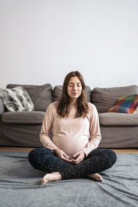 Young woman sitting on sofa at home